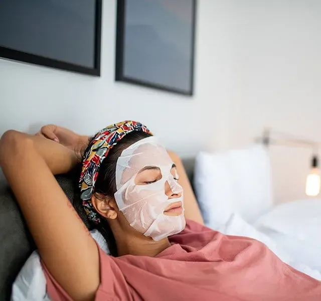 Woman resting with a sheet face mask